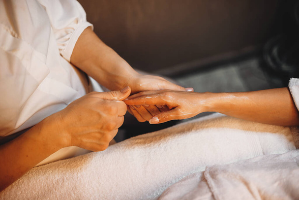 Mujer caucásica teniendo una sesión de spa para sus dedos de la mano en un joven terapeuta
 - Foto, imagen