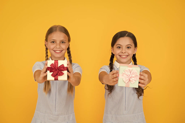 Share happiness. Holiday celebration. Sharing gifts. Girls opening gifts yellow background. Classmates giving gifts boxes. Educational program for gifted kids. School holiday. Upbringing generosity - Foto, immagini