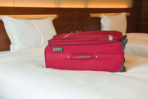 roter Koffer auf Bett im Hotelzimmer - Foto, Bild