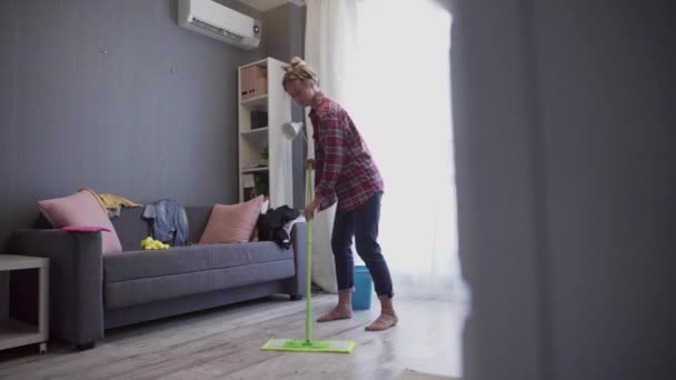 Beautiful young woman cleaning floor with mop. - Materiał filmowy, wideo