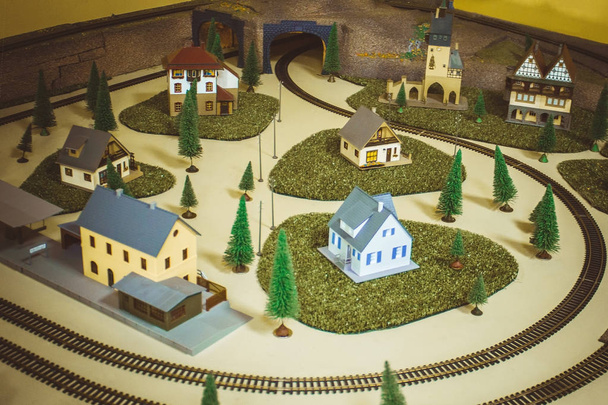 ミニチュア、おもちゃの家や木の小さな町。トンネルを離れる。レールの周り、鉄道。ヴィンテージトーン、ヴィネット。上からの眺め. - 写真・画像