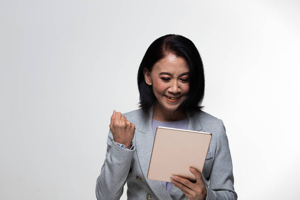 Azji lat 50. lat 60-tych Business Woman Stand in grey Formal Suit touch screen tablet, studio lighting grey background isolated, Senior Boss kobieta z krótkimi włosami ręce szczęśliwy uśmiech kierunek - Zdjęcie, obraz