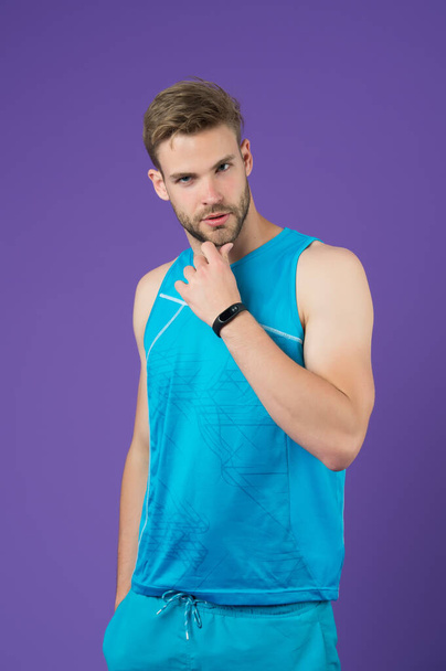 handsome man touch beard. man in sportswear. muscular guy purple background. Portrait of attractive athlete. fit man relax after exercising in gym. male fitness fashion. fitness and healthy lifestyle. - Foto, Imagem