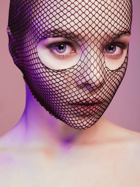 Beautiful Woman in Net on her Face lighted in pink. Pretty Girl in lace mask - Photo, Image