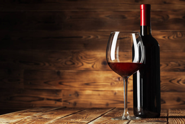 Ahşap zemin üzerinde lezzetli kırmızı şarap bulunan cam ve şişe. Yaratıcı fotoğraf. - Fotoğraf, Görsel