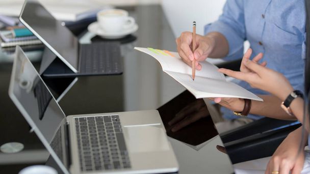 Boční pohled dvou podnikatelů brainstorming na jejich úkol s notebookem, notebookem a digitálním tabletem na černém stole - Fotografie, Obrázek