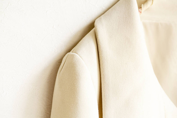 beige or white jacket hanging on clothes hanger on white background.close up. - Photo, Image