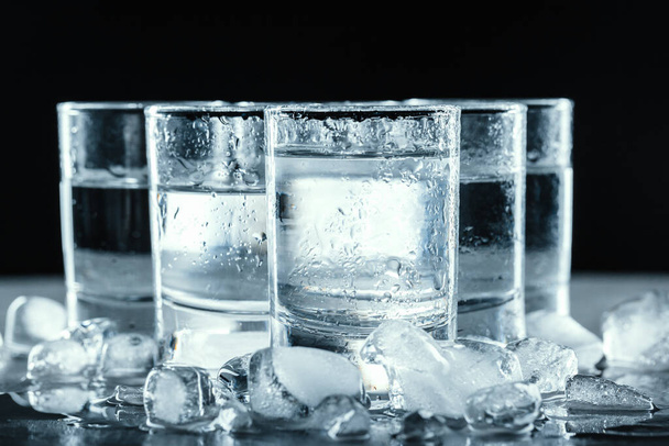 Cold vodka in shot glasses on a black background. - Φωτογραφία, εικόνα