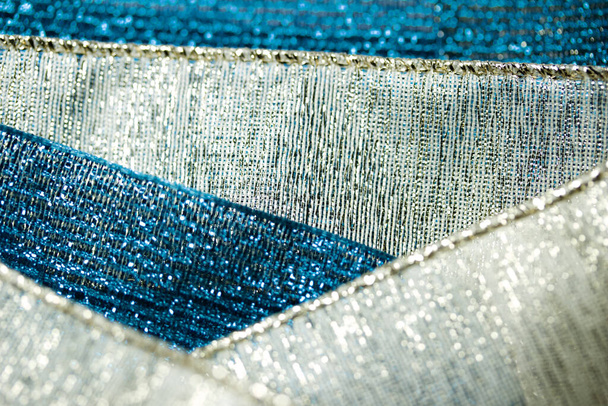 Macro abstract background of shimmering blue and gold fabric ribbon textures with bokeh - Photo, Image