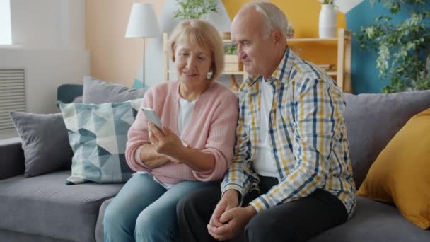 Happy people elderly couple enjoying social media using smartphone at home - Metraje, vídeo
