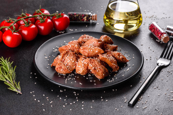 Куриное филе в кунжуте, соус терияки на черной каменной тарелке. Азиатская кухня
 - Фото, изображение
