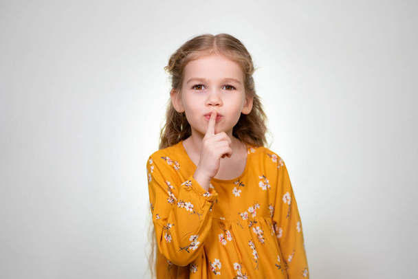 Sign quieter fingers shows beautiful little girl - Foto, afbeelding
