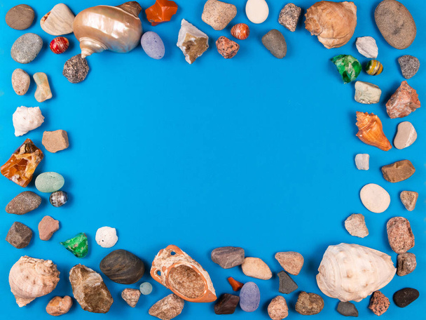 Photo frame of sea shells and pebble on bright blue background with space for your text or photo - Zdjęcie, obraz
