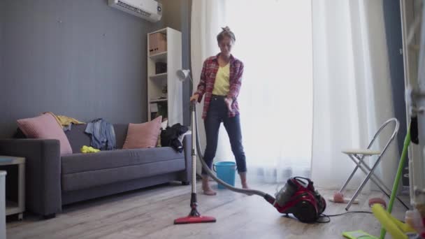 Woman using vacuum cleaner listen to music and dancing - Felvétel, videó