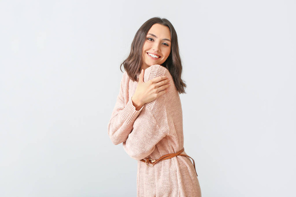 Όμορφη νεαρή γυναίκα σε ζεστό πουλόβερ στο φως φόντο - Φωτογραφία, εικόνα