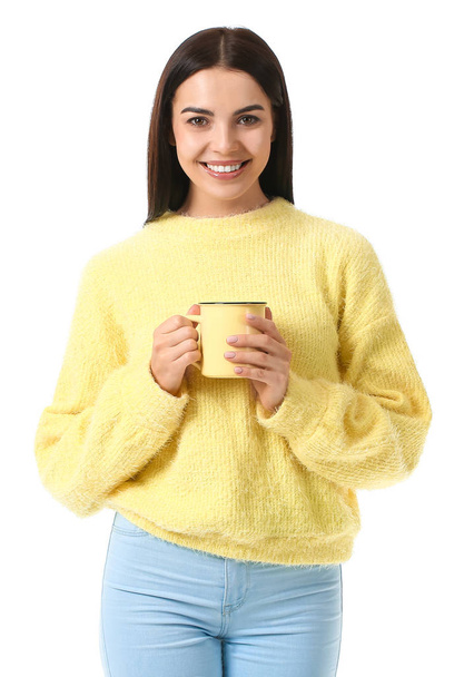 Beautiful young woman in warm sweater drinking tea on white background - Фото, изображение