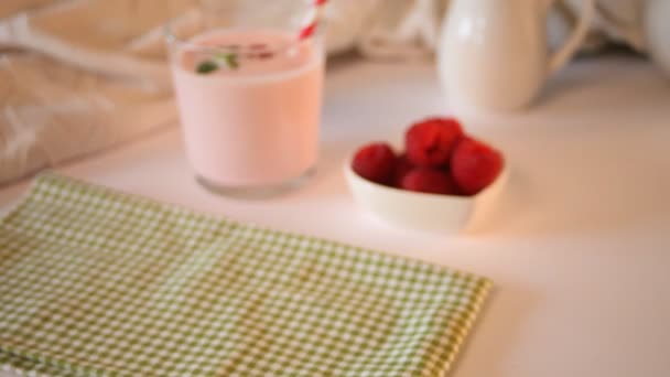 Woman hand put on the table glass of natural homemade yogurt with fresh raspberry. Breakfast concept - Footage, Video
