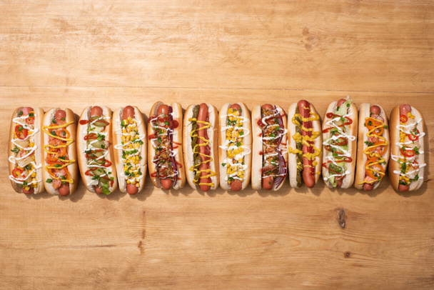 top view of fresh delicious hot dogs on wooden table - Zdjęcie, obraz