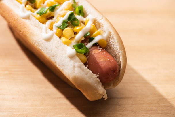 close up view of delicious hot dog with corn, green onion and mayonnaise on wooden table - Photo, Image