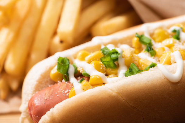 close up view of delicious hot dog with corn, green onion and mayonnaise near french fries - Photo, Image