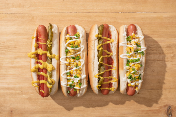 flat lay with delicious hot dogs with corn, green onion and pickles on wooden table - Photo, Image