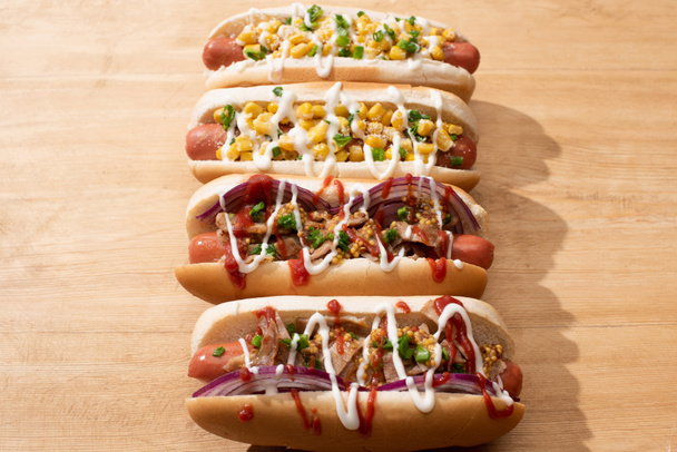 delicious hot dogs with red onion, bacon and corn on wooden table - Φωτογραφία, εικόνα