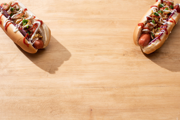 delicious hot dogs with red onion, bacon and Dijon mustard on wooden table - Photo, Image