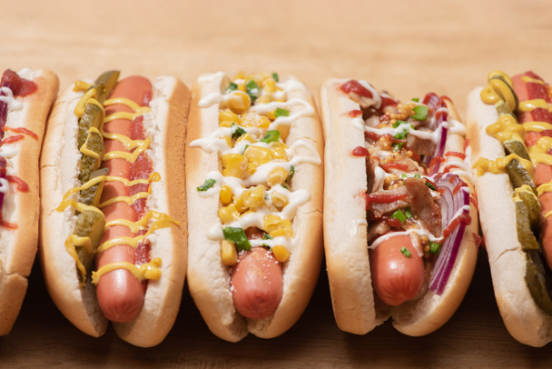 fresh various tasty hot dogs with vegetables and sauces on wooden table - Fotografie, Obrázek