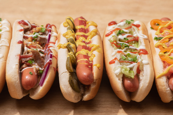 fresh various tasty hot dogs with vegetables and sauces on wooden table - Foto, Imagem