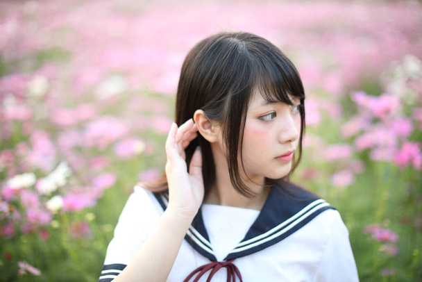 Pembe kozmos çiçekli Japon kız üniformasının portresi.  - Fotoğraf, Görsel