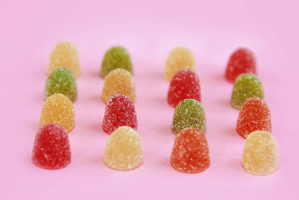 круглый сладкий разноцветный конфетный мармелад в сахарной крошке на розовом фоне
 - Фото, изображение