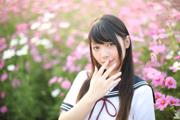 Pembe kozmos çiçekli Japon kız üniformasının portresi.  - Fotoğraf, Görsel