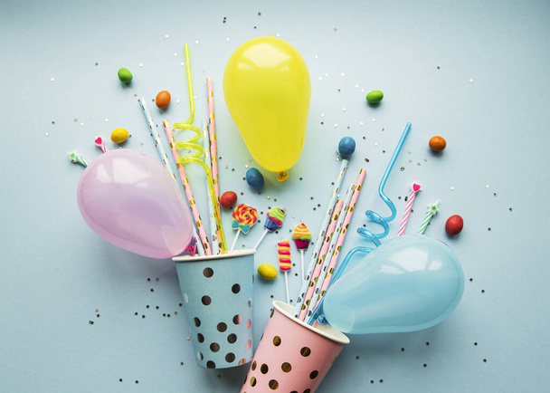 Gorras de fiesta de cumpleaños, pajitas de papel, dulces y globos sobre fondo azul
 - Foto, imagen