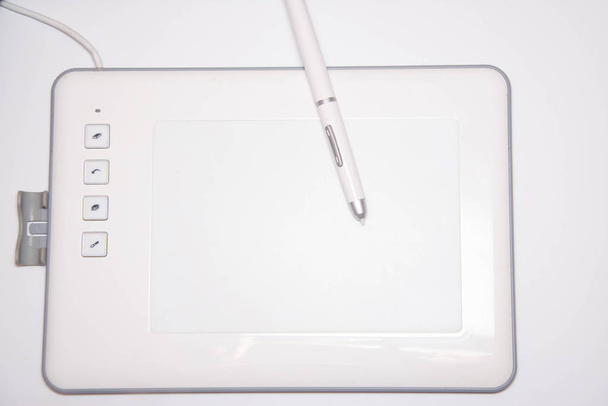 White graphics tablet on a white background. The work of a graphic designer. View of the top, side view. Tablet in macro. Pen stylus for drawing. Buttons on the tablet. - Photo, Image