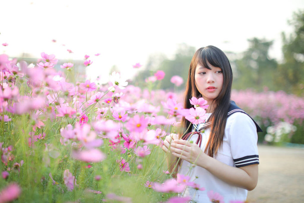 Portret van Japans schoolmeisje uniform met roze kosmos bloem  - Foto, afbeelding