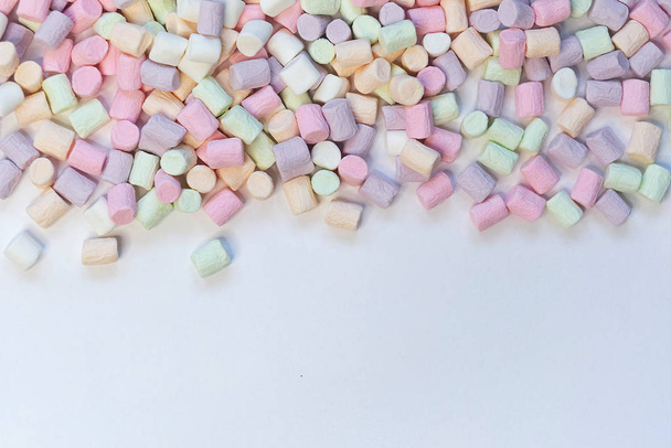Draufsicht auf pastellfarbene Marshmallow-Bonbons mit einigen auf dem blassweißen Tisch - Foto, Bild