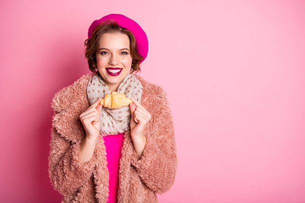 Photo of pretty lady traveler hold fresh croissant morning snack abroad trip wear casual stylish fur coat scarf beret cap outfit clothes isolated pink color background - Φωτογραφία, εικόνα