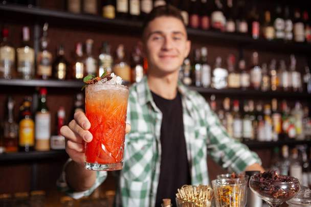 Selectieve focus op cocktailglas vrolijke barman houden uit naar de camera - Foto, afbeelding