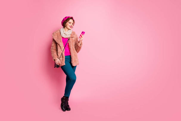 Full body photo of cute lady hold telephone chatting friends walk down street wear casual stylish spring fur coat scarf beret pants shoes clutch outfit isolated pink color background - Foto, afbeelding