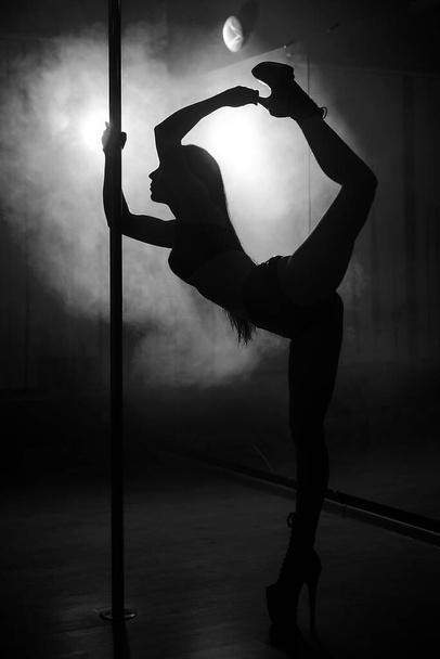 junge Frau tanzt Striptanz und hebt den Fuß in den Hinterkopf - Foto, Bild