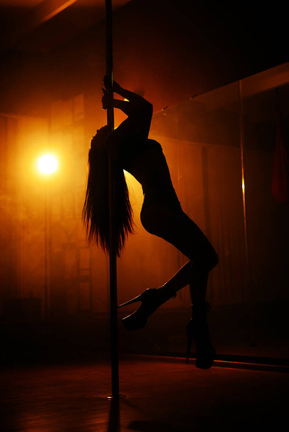 silhouette of a girl on a background of light that dances striptease - Zdjęcie, obraz