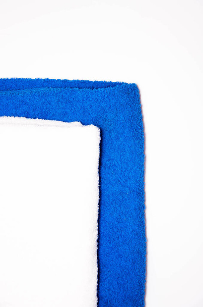 Ironed towels in blue and white on a white background. View from the top, side. Macro. Place for text. Towels on the table and in the foreground a green potted flower - Photo, Image