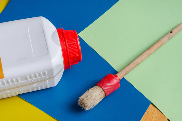 Top view of a white container with a red lid. Round paint brush on a colorful background. Home repair, design or craft. Close-up. Selective focus. - Photo, Image