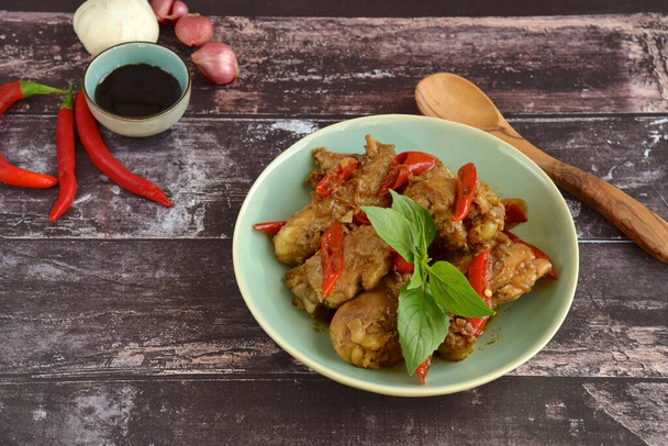 Ayam Kecap - chicken cooked or stew in thick soy sauce and spices. Garnish with chili and Thai basil. Famous food in South East Asia - Фото, изображение
