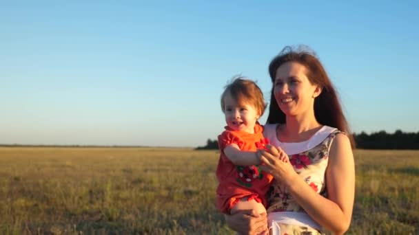 Anya és baba sétál a természetben. Boldog anya sétál a babával a karjaiban. Anya és a kislánya egy vidéki úton sétálnak egy búzamezőn.. - Felvétel, videó
