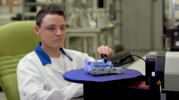 insinööri skannaa korkealaatuisen muovikomponentin 3D-skannerilla, pyörivä alusta ohjaussauvalla
 - Materiaali, video