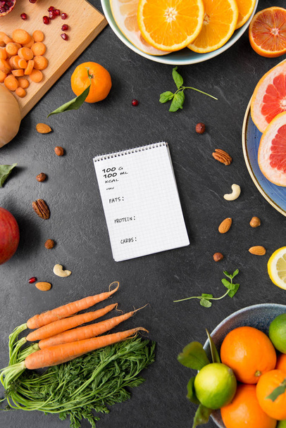 close up of notebook, fruits and vegetables - Foto, afbeelding
