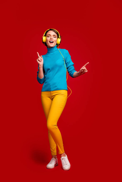 Teljes hosszúságú fotó álmodozó izgatott lány ifjúsági headset hallgatni zenét élvezni rádió dal tánc mozog ujjak viselet ragyog divatos ruhát elszigetelt piros háttér - Fotó, kép