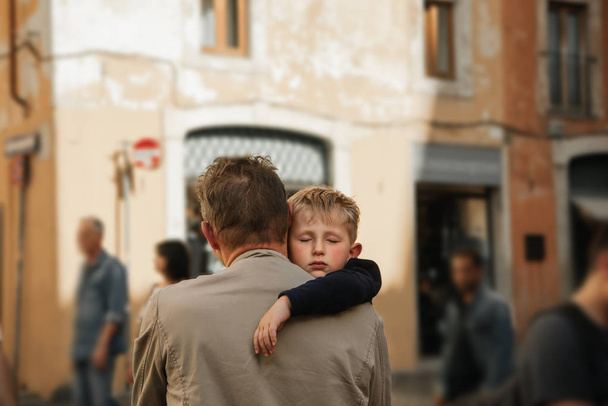 Niño turista durmiendo al hombro de su padre durante la larga caminata por la ciudad. Niño Cansado de caminar y dormido
 - Foto, Imagen