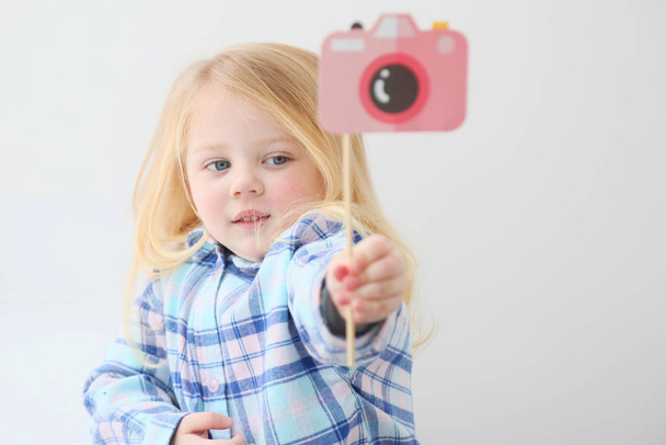 The child with a toy photo camera, which is a picture. This girl is a cute blonde kid/ She is smiling. This is an illustration for photo class for preschooler or English school. Isolate, copy space. - Fotoğraf, Görsel